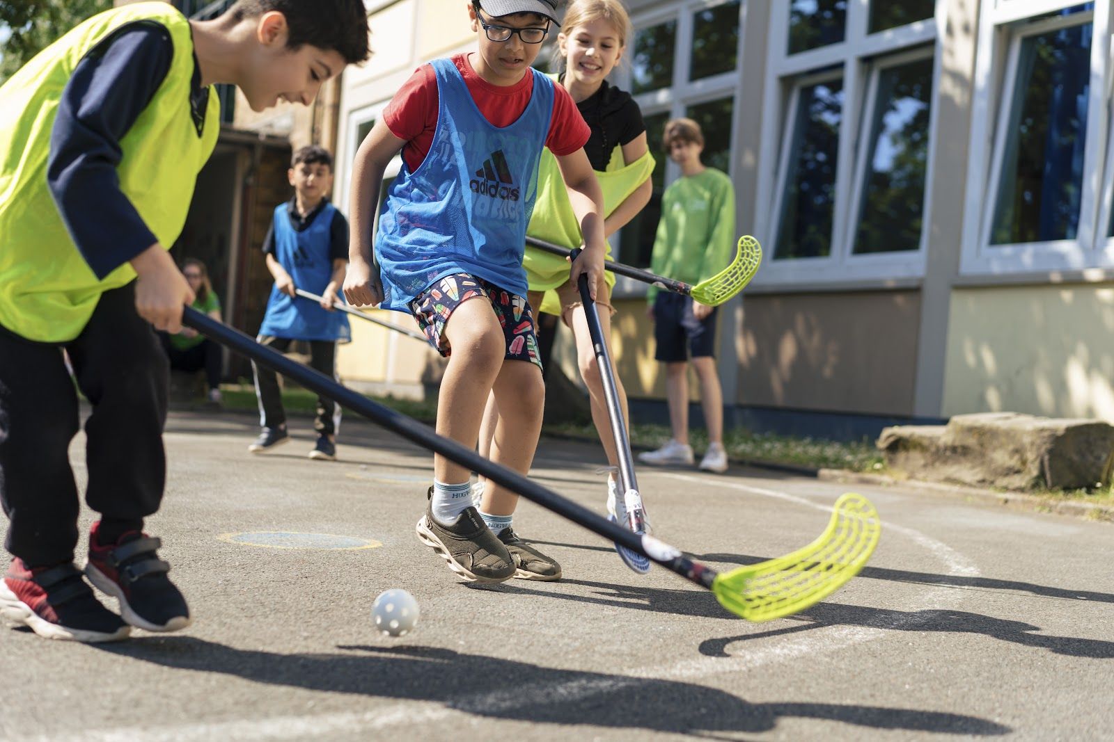 Kinder spielen Floorball auf dem Schulhof