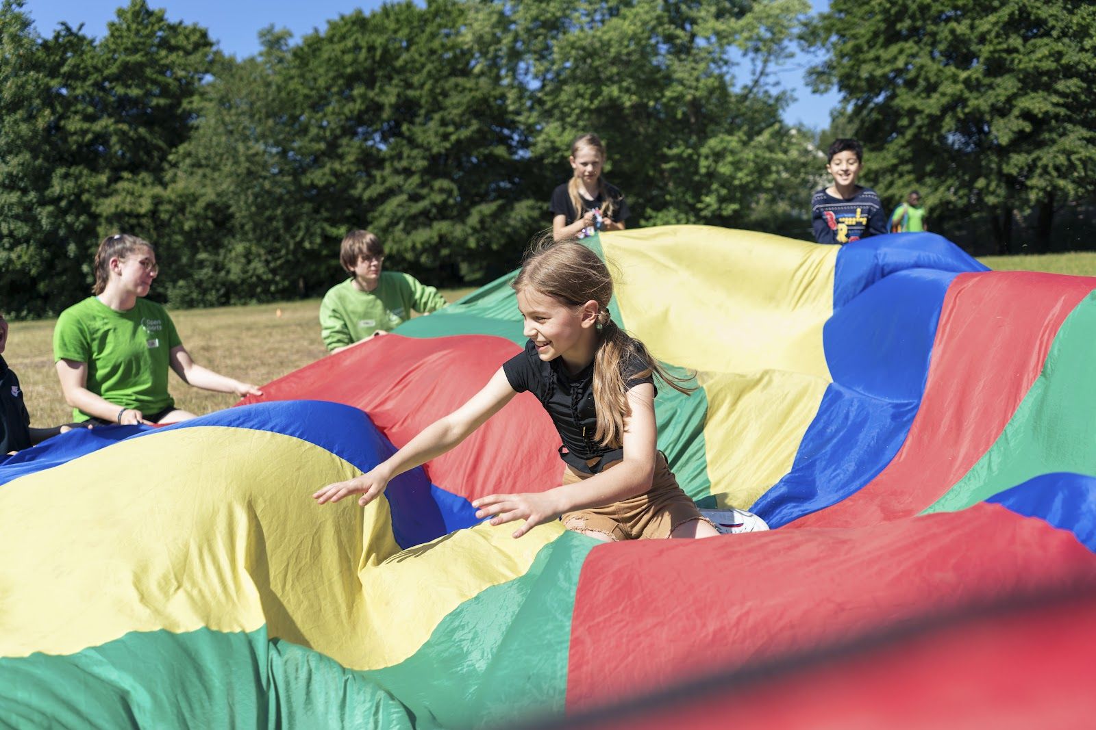 Kinder spielen mit einem bunten Schwungtuch auf der Wiese
